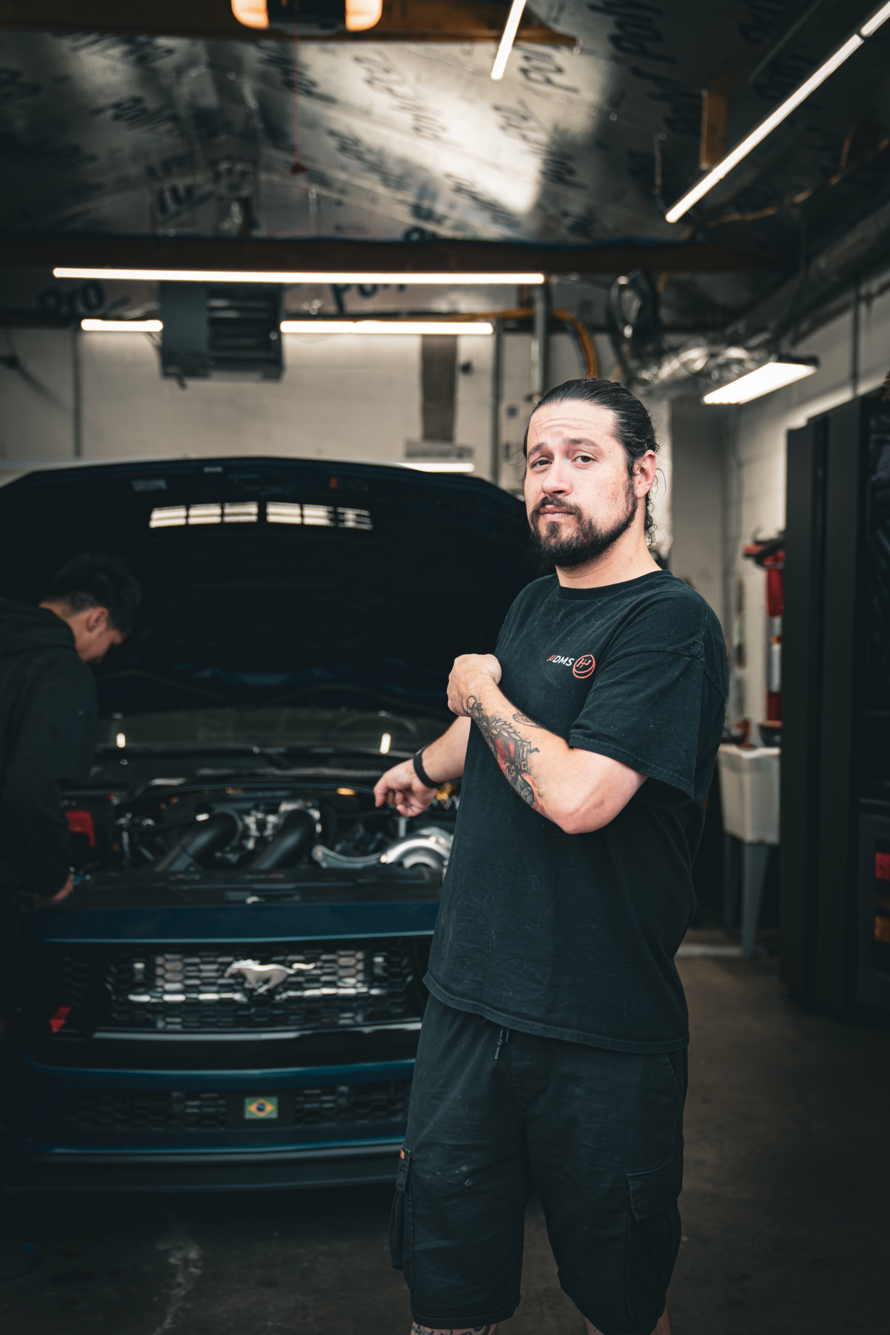 Dave, founder of Dave's Mechanic Shop, beside a performance Mustang in the DMS workshop