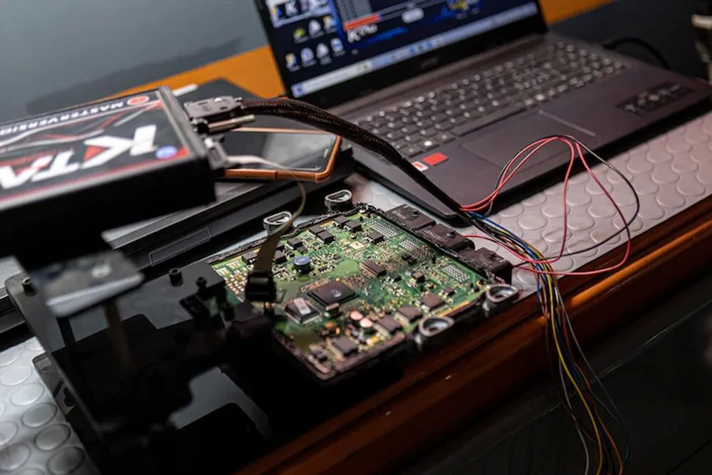 Automotive engine control module connected to calibration equipment and a laptop