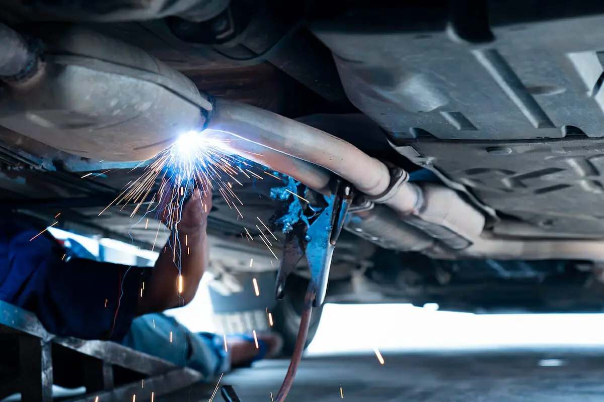 Automotive exhaust pipe being welded beneath a vehicle